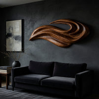 Layered swoosh carved wooden wall sculpture on a dark charcoal plaster wall
