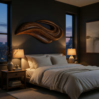 Layered swoosh carved wooden wall sculpture above a bed in a dusk lit bedroom