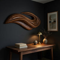 Layered swoosh carved wooden wall sculpture above a desk in a dark study corner