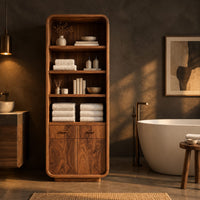Tall bathroom cabinet with four open shelves above two small drawers and two doors in a dark bathroom at golden hour