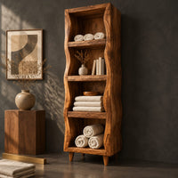 Corner detail of tall narrow cabinet with wavy side panels and four open shelves beside wood, brass and linen samples