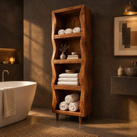 Tall narrow cabinet with wavy side panels and four open shelves in a dark bathroom at golden hour