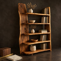 Corner detail of bookshelf with five shelves and a tall slab side with a wavy outline beside wood, brass and linen samples