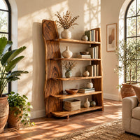 Bookshelf with five shelves and a tall slab side with a wavy outline in a bright living room with arched windows and plants