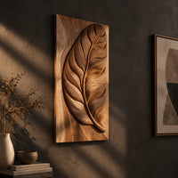 Tall wood panel carved in deep relief with one large leaf and fine veins on a dark charcoal plaster wall