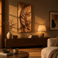 Tall wood panel carved in deep relief with one large leaf and fine veins above a low console in an evening living room