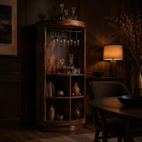 Tall cylinder bar cabinet with a glass rail on top and open cubbies below in an evening dining room with walnut wall paneling