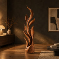 Tall flame sculpture of layered leaf blades rising from a smooth base in a dark living room at golden hour