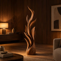 Tall flame sculpture of layered leaf blades rising from a smooth base in an evening living room with walnut wall paneling