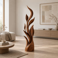 Tall flame sculpture of layered leaf blades rising from a smooth base in a Scandinavian living room with white walls