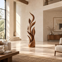 Tall flame sculpture of layered leaf blades rising from a smooth base in a bright open plan living room