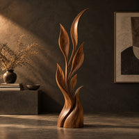 Wood sculpture of a slim leafy stem with pointed leaves and a sculpted base, three-quarter view showing the grain