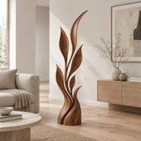 Wood sculpture of a slim leafy stem with pointed leaves and a sculpted base in a Scandinavian living room with white walls