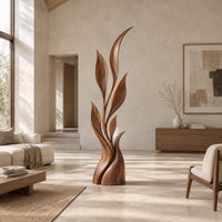 Wood sculpture of a slim leafy stem with pointed leaves and a sculpted base in a bright open plan living room