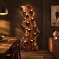 Tall live edge slab wine rack with angled bottle pegs in a dark dining room at golden hour