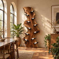 Tall live edge slab wine rack with angled bottle pegs in a bright dining room with arched windows and plants