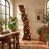 Tall wine rack made from a live edge slab with staggered pegs in a bright dining room with arched windows and plants