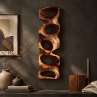 Detail of tall wooden wall sculpture with five stacked organic openings beside wood, brass and linen samples