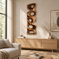 Tall wooden wall sculpture with five stacked organic openings above a light oak sideboard in daylight