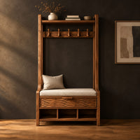 Tall wood storage bench with coat hooks and three open cubbies in a dark studio against a charcoal plaster wall