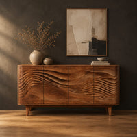 Sideboard with four wave carved doors and tapered legs in a dark studio against a charcoal plaster wall