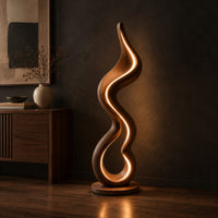Floor lamp made of one flowing ribbon that ends in a teardrop loop, three-quarter view showing the grain