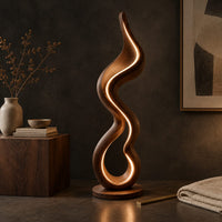 Corner detail of floor lamp made of one flowing ribbon that ends in a teardrop loop beside wood, brass and linen samples