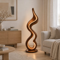 Floor lamp made of one flowing ribbon that ends in a teardrop loop in a Scandinavian living room with white walls