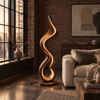 Floor lamp made of one flowing ribbon that ends in a teardrop loop in an industrial loft living room with exposed brick