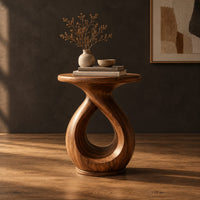 Round side table on a looped teardrop pedestal with a flat disc base in a dark studio against a charcoal plaster wall