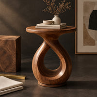 Corner detail of round side table on a looped teardrop pedestal with a flat disc base beside wood, brass and linen samples