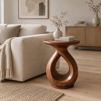 Round side table on a looped teardrop pedestal with a flat disc base in a Scandinavian living room with white walls