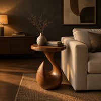 Circular side table on a teardrop pedestal with a swirling neck in a dark living room at golden hour