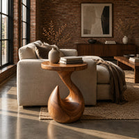 Circular side table on a teardrop pedestal with a swirling neck in an industrial loft living room with exposed brick