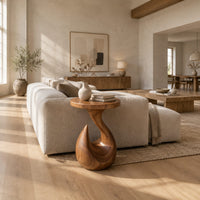 Circular side table on a teardrop pedestal with a swirling neck in a bright open plan living room