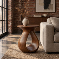 Teardrop side table with a flared top and an open loop body in an industrial loft living room with exposed brick