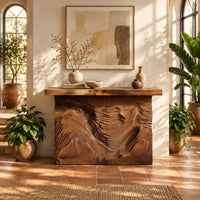 Console table with deep ridged terrain carving across the front in a bright entryway with arched windows and plants