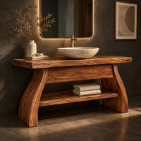 Corner detail of freestanding vanity with a thick slab top, flared legs and a low shelf beside wood, brass and linen samples
