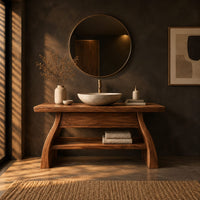 Freestanding vanity with a thick slab top, flared legs and a low shelf in a dark bathroom at golden hour