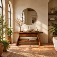 Freestanding vanity with a thick slab top, flared legs and a low shelf in a bright bathroom with arched windows and plants