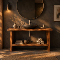 Bathroom vanity with a thick slab top, plank legs and a low shelf in a dark bathroom at golden hour