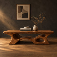 Thick slab coffee table with a carved cutout base in a dark studio against a charcoal plaster wall