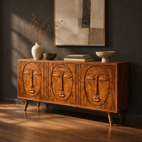 Three door sideboard with carved face reliefs and tapered angled legs, three-quarter view showing the grain