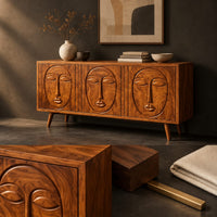 Corner detail of three door sideboard with carved face reliefs and tapered angled legs beside wood, brass and linen samples