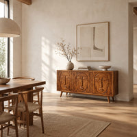 Three door sideboard with carved face reliefs and tapered angled legs in a bright open plan dining room