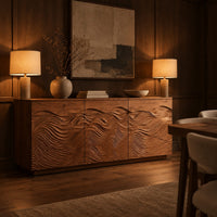 Low sideboard with three doors carved in flowing waves on a plinth base in an evening dining room with walnut wall paneling