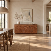 Low sideboard with three doors carved in flowing waves on a plinth base in a bright open plan dining room