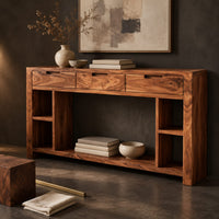 Corner detail of console table with three drawers, open side cubbies and a lower shelf beside wood, brass and linen samples