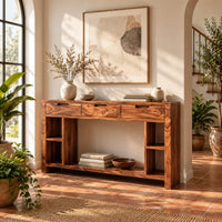Console table with three drawers, open side cubbies and a lower shelf in a bright entryway with arched windows and plants