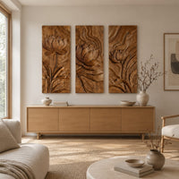 Set of three tall wooden panels carved with lotus flowers in relief above a light oak sideboard in daylight